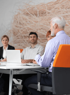 ceo in meeting with company leaders with orange chair