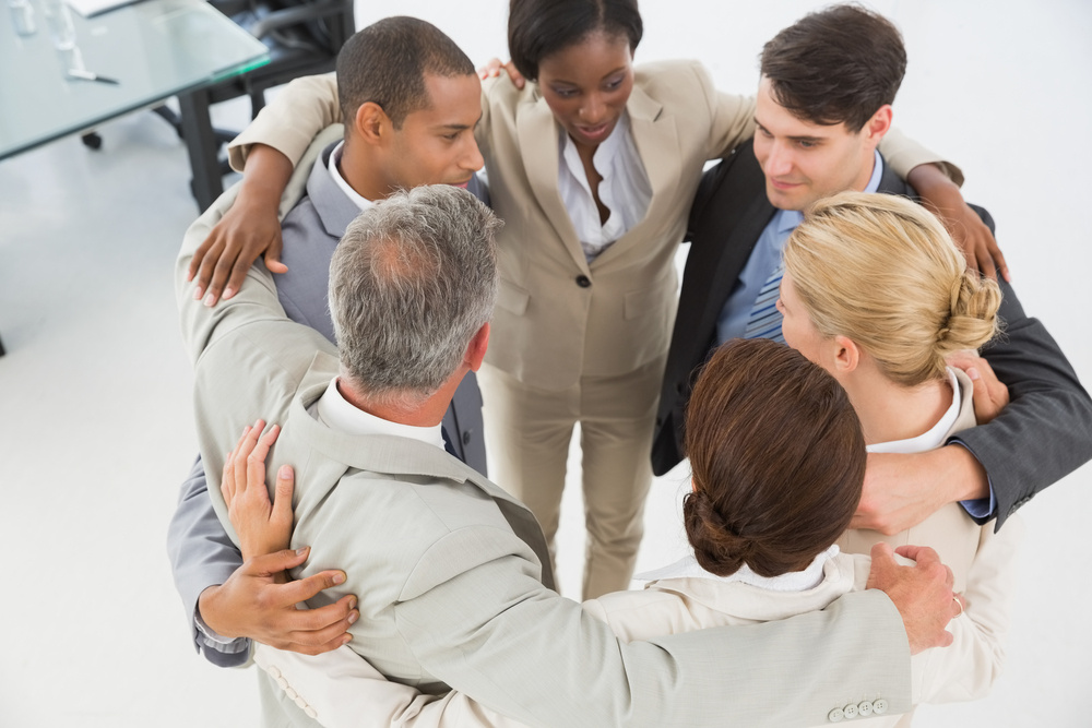 Diverse business team hugging in a circle in the office