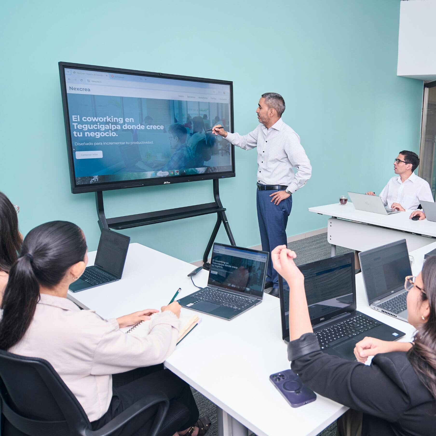 Professional team engaged in a business presentation with laptops and a projector screen.