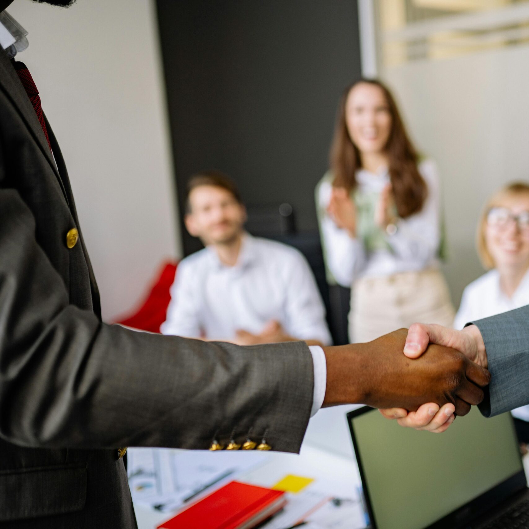 Close-up of a handshake between colleagues in a professional office setting, emphasizing teamwork and agreement.